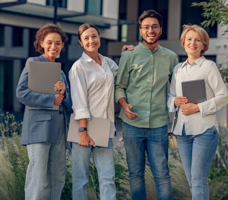 Group of diverse business people standing on background of modern office building and looks camera Professional business team standing on background of modern office building and looks camera